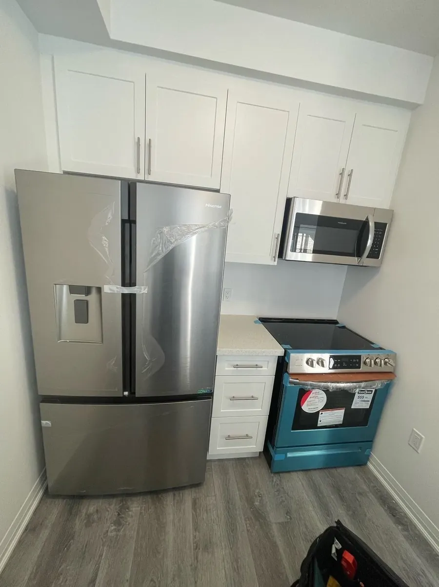 French-door fridge, range and over-the-range microwave newly installed in a white kitchen
